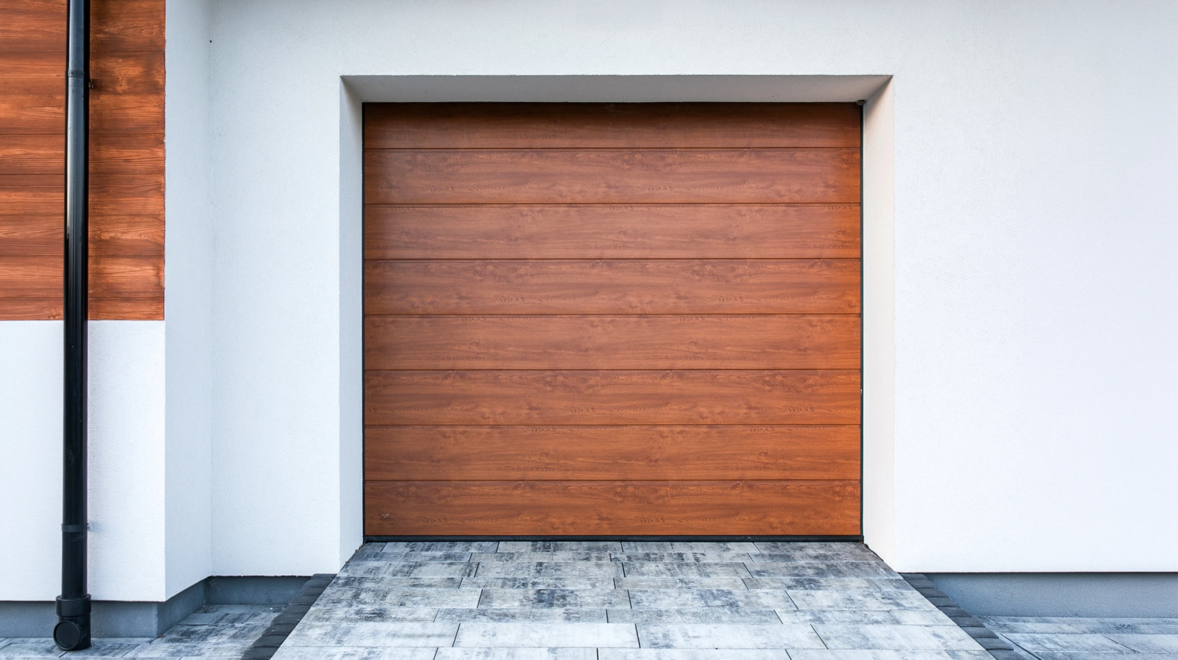 Entrée résidentielle avec portail automatique en métal noir à barreaux horizontaux, piliers en briques rouges avec luminaires intégrés