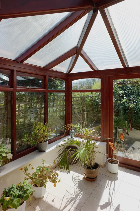 Jardin d'hiver avec serre en polycarbonate transparent située dans un jardin résidentiel givré au petit matin