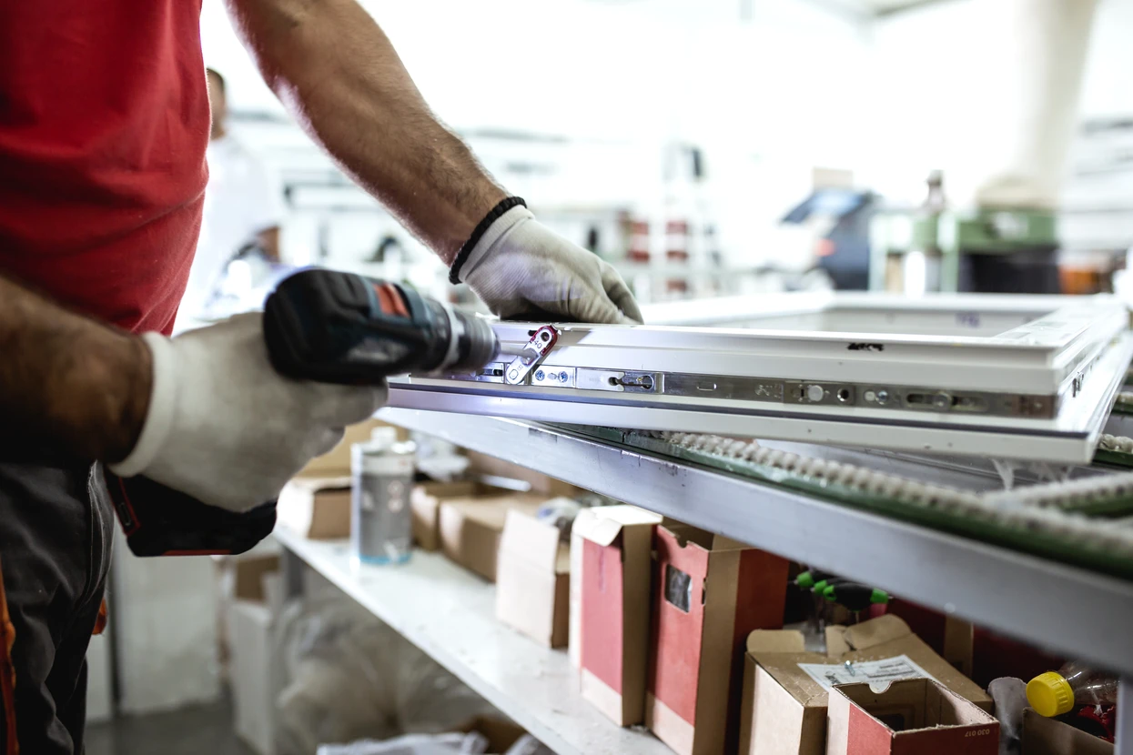 Intérieur d'atelier menuiserie avec établi en bois naturel, étagères murales compartimentées contenant outils et matériaux organisés